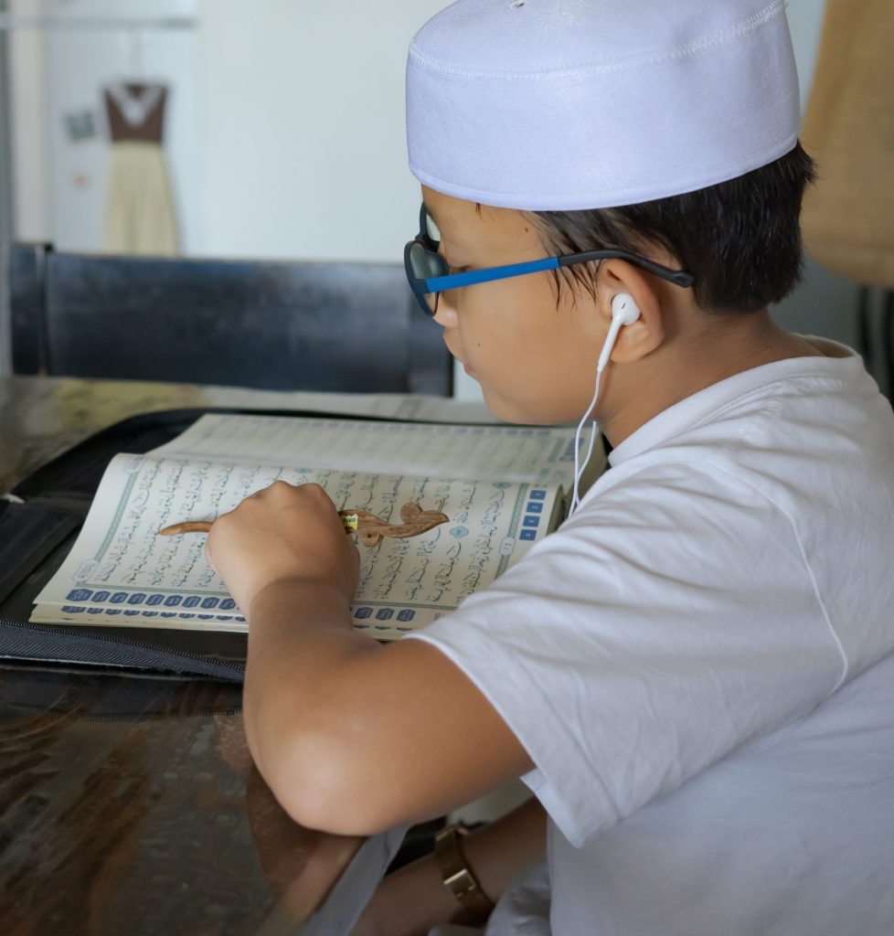 Asian kid reading Al-Quran through video call during education